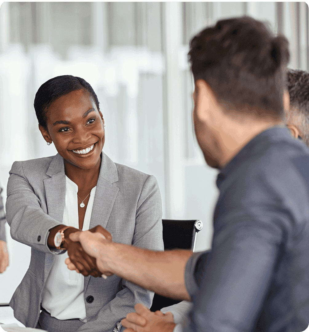 Two professionals shaking hands in a meeting room, smiling.
