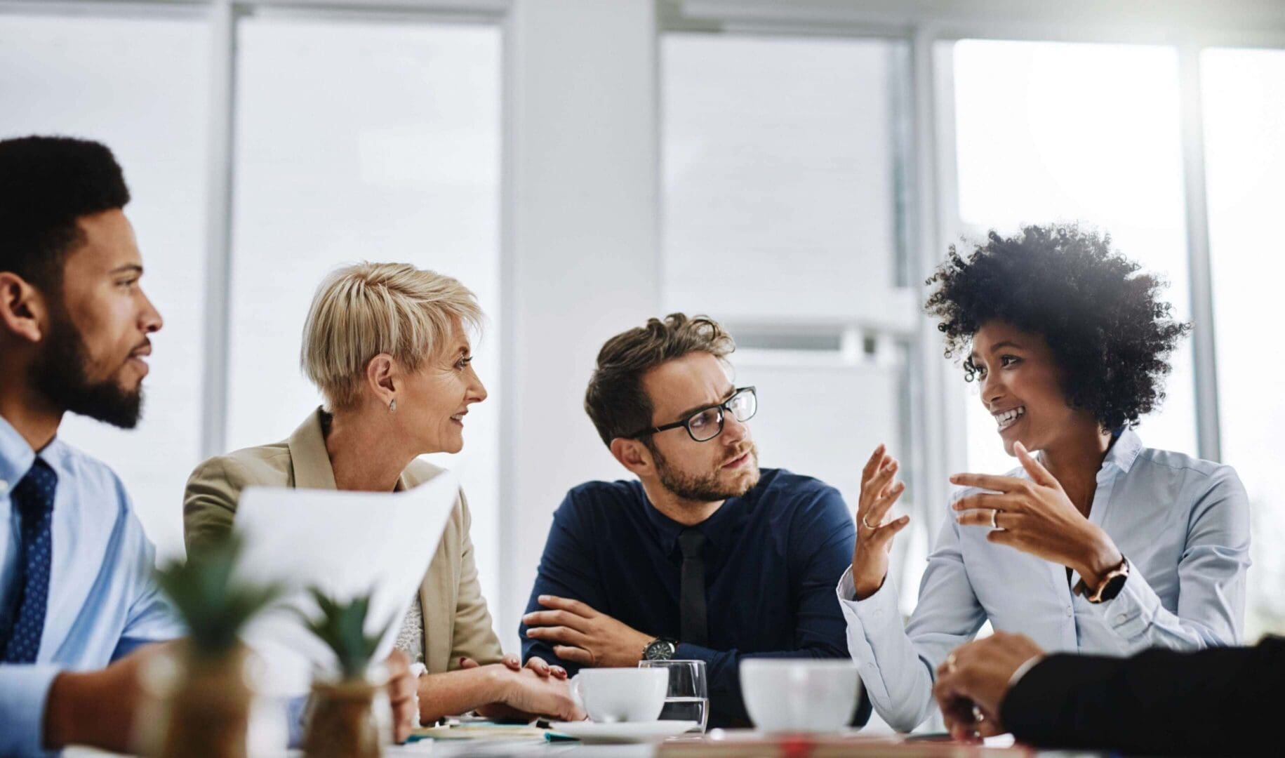 Colleagues engaged in a lively discussion around a table in a modern office.