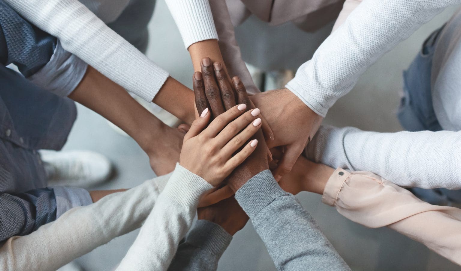 Diverse hands stacked together symbolizing unity and teamwork.
